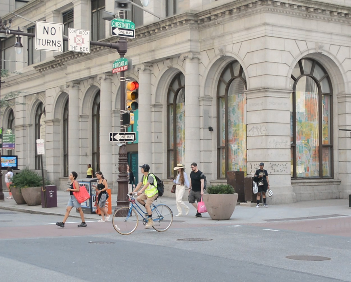 exterior photo of the Land Title Building, pedestrians and cyclists cross the busy street