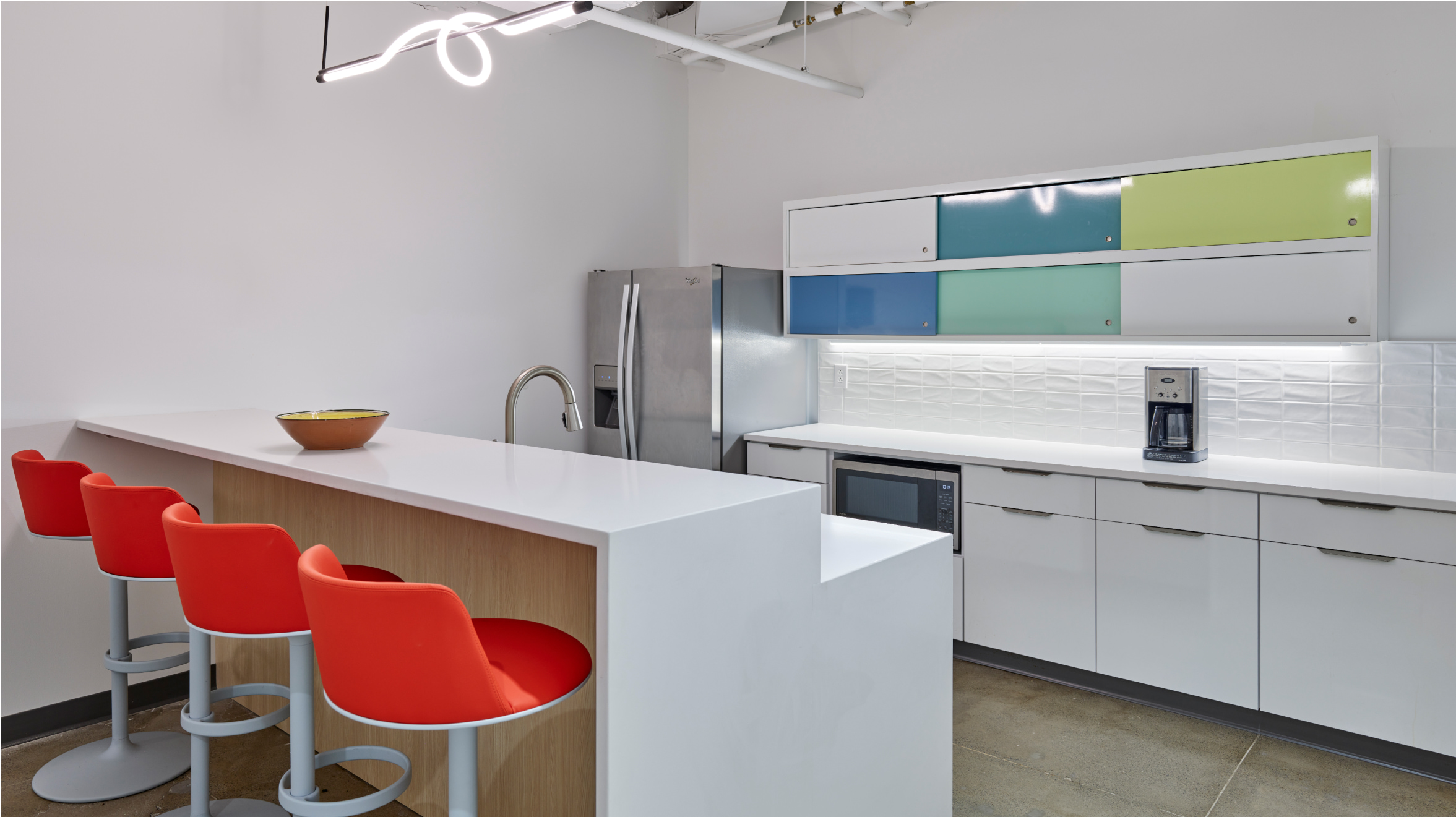 CPA kitchen with an island table, four red chairs, kitchen appliances and bright colored cabinets