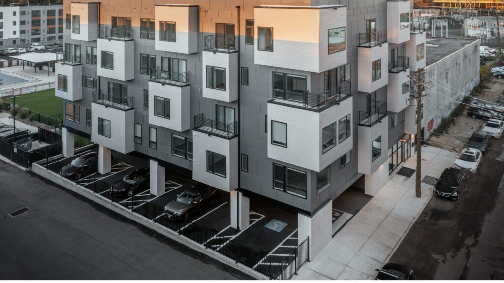 Multi-unit apartment exterior with some extruded windows/balconies - aerial view with cars parked