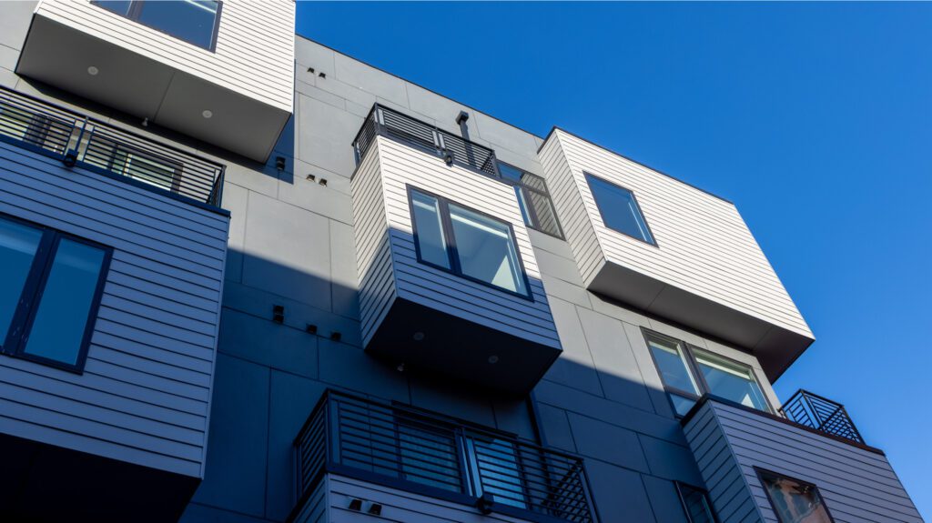 Multi-unit apartment exterior with some extruded windows/balconies - view from the ground with shadow