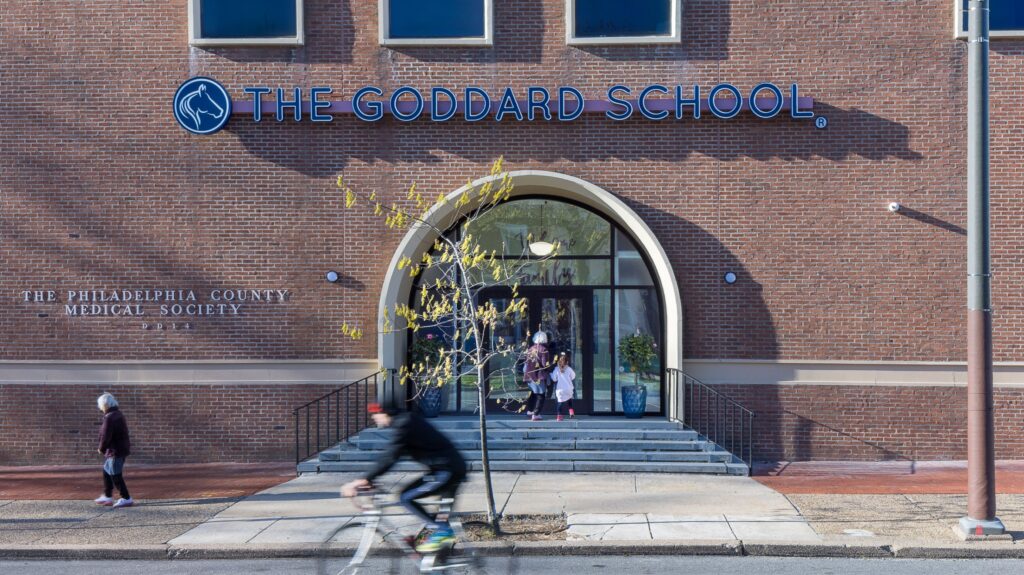 The Goddard School entrance with the students walking in and people passing by
