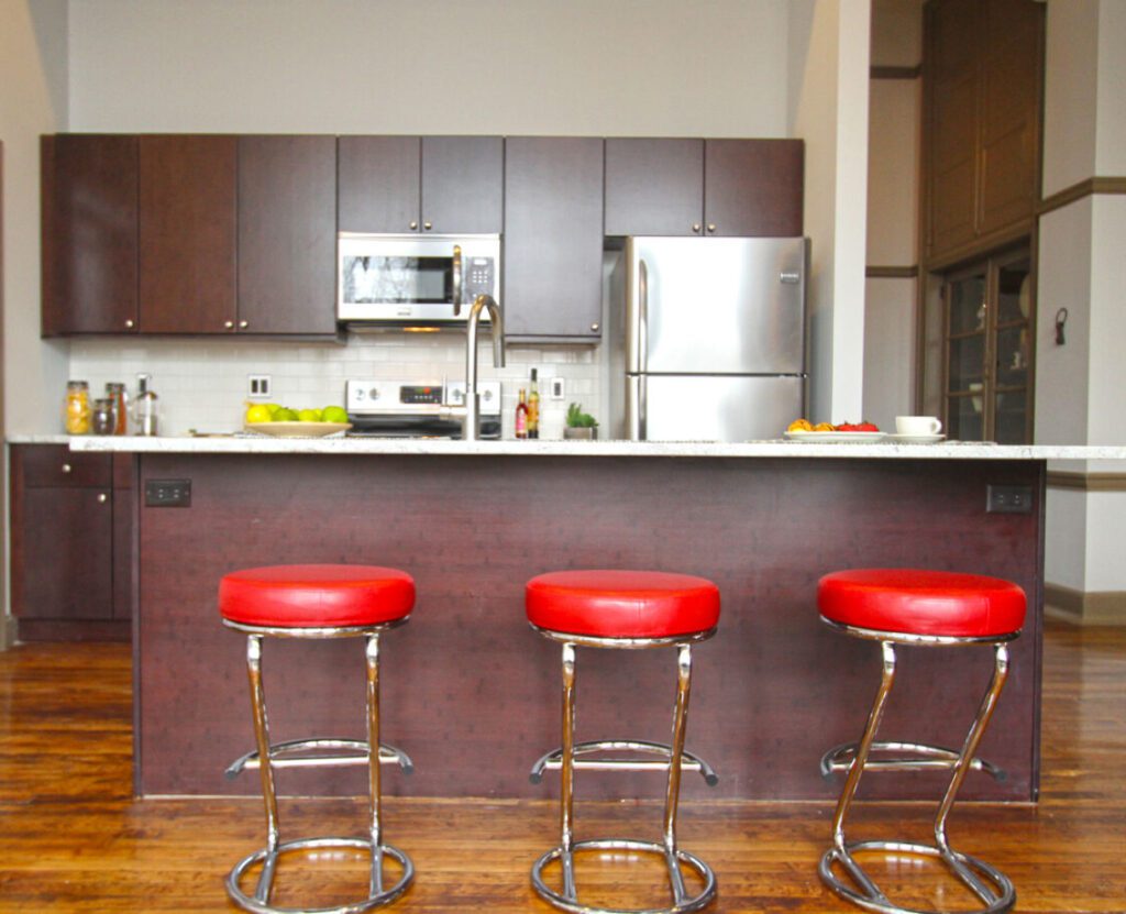 Warton Street Lofts kitchen area with an island table and three red chairs