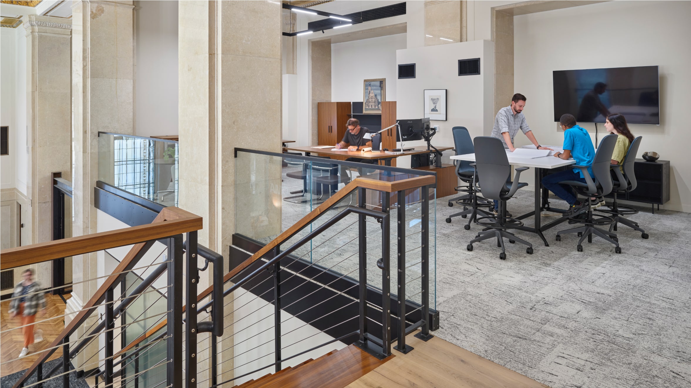 Office area on the second floor. People are having a meeting, looking at papers on the desk