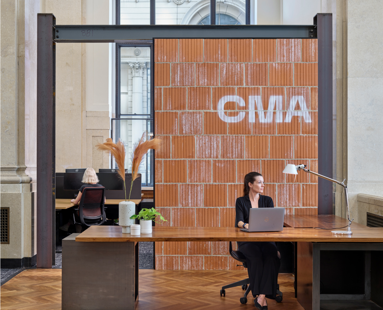CMA reception desk where a woman is sitting behind a laptop, gazing out the window.
