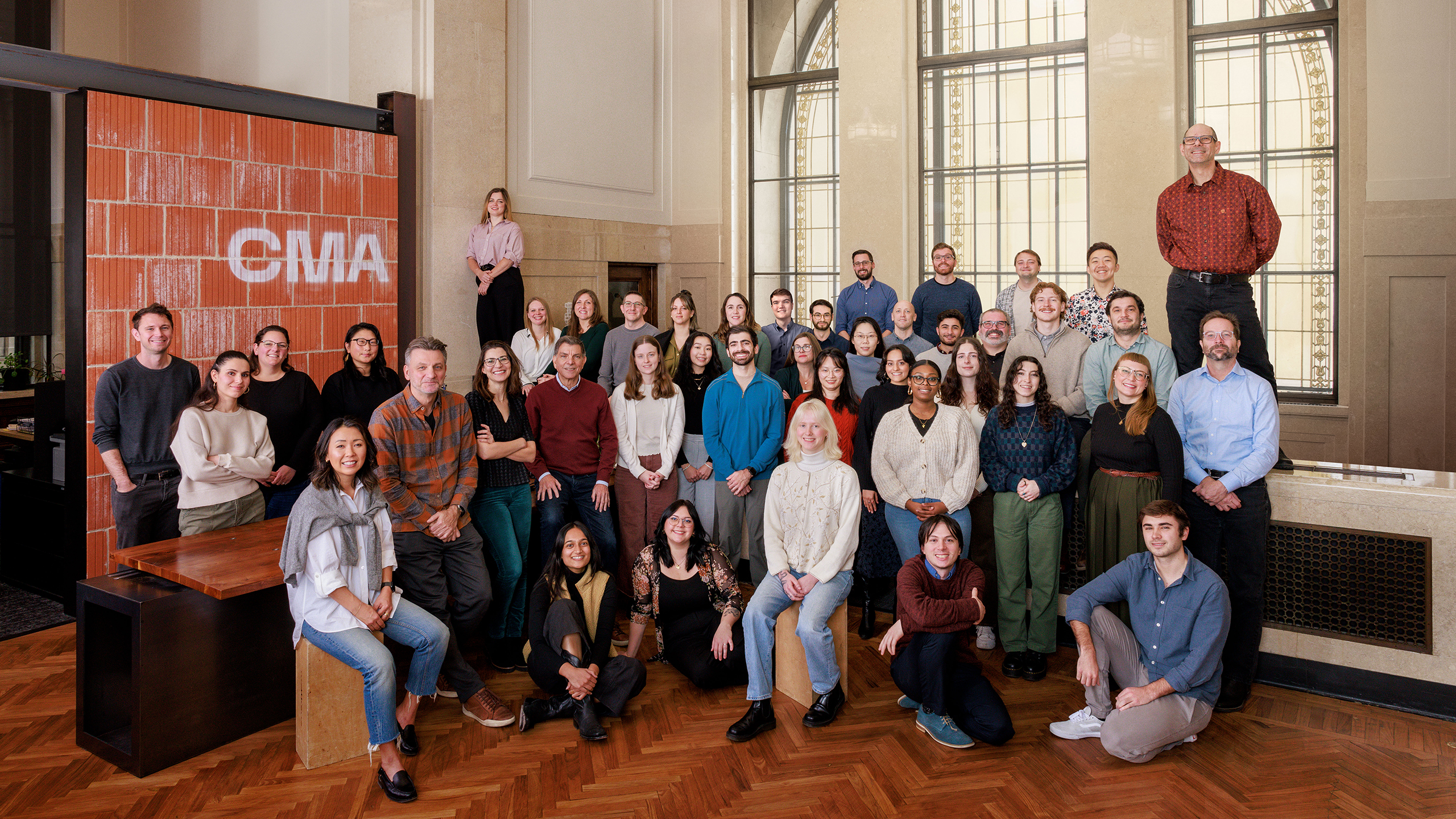 a group photo of the firm's 43 employees in their office's reception area