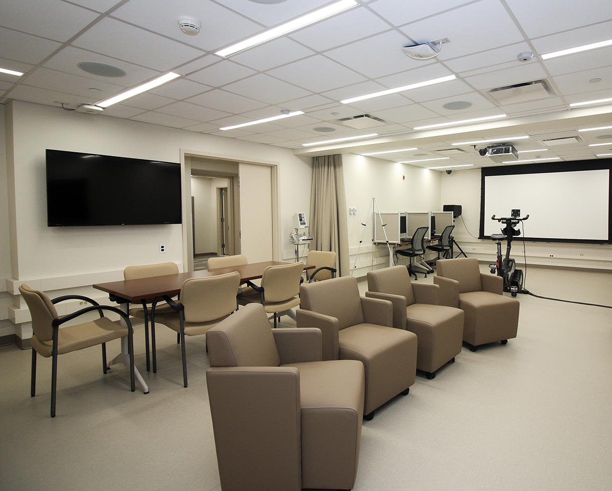 a common seating area that contains equipment such as an exercise bike, projector, and computers with privacy screens