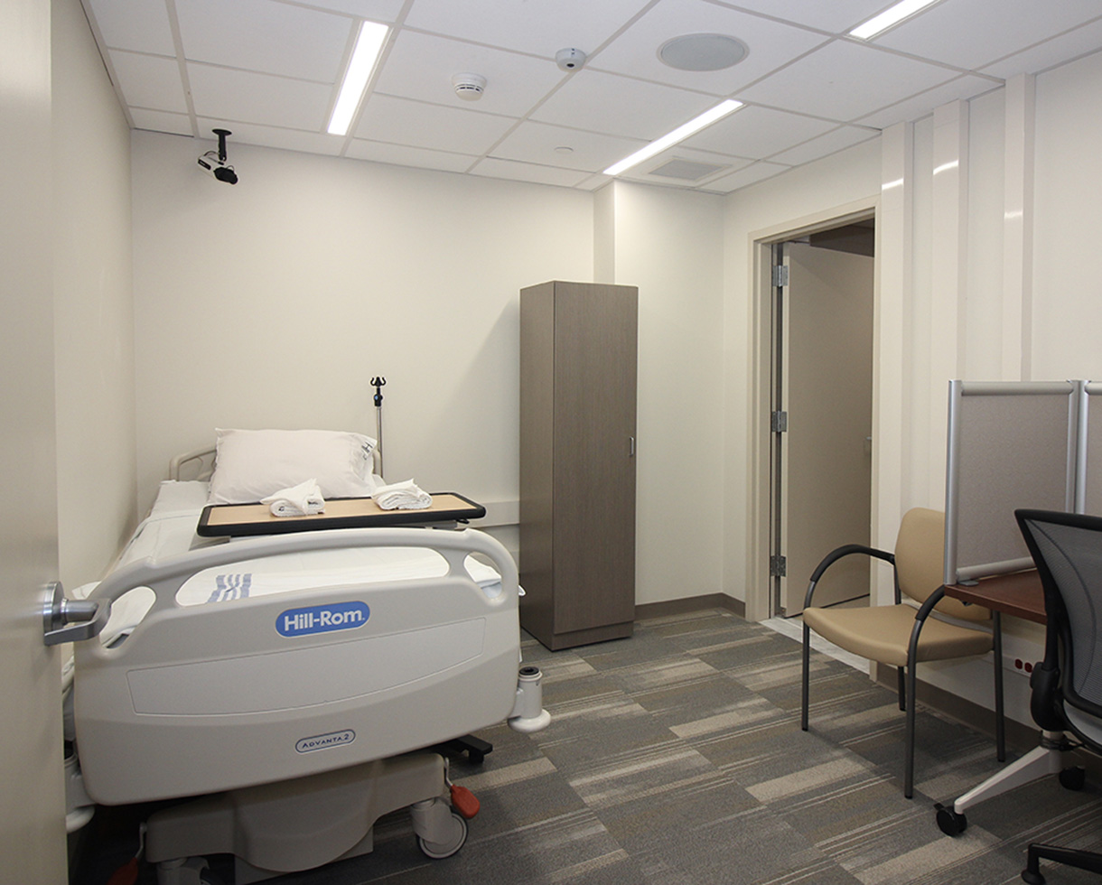 an exam room containing a bed, cabinet, and desk