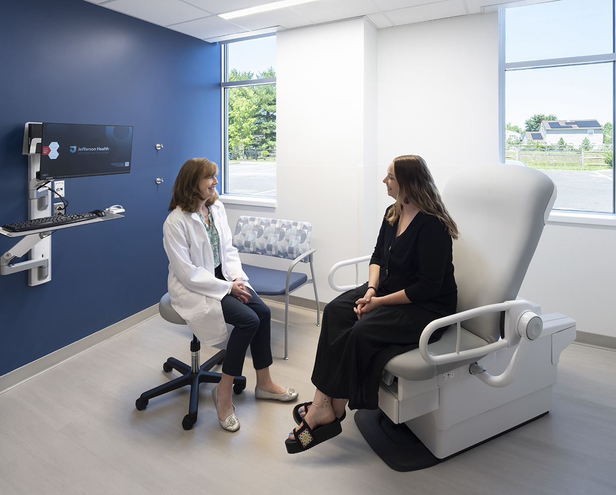 photo of a clinic exam room, showcasing a doctor speaking with a patient