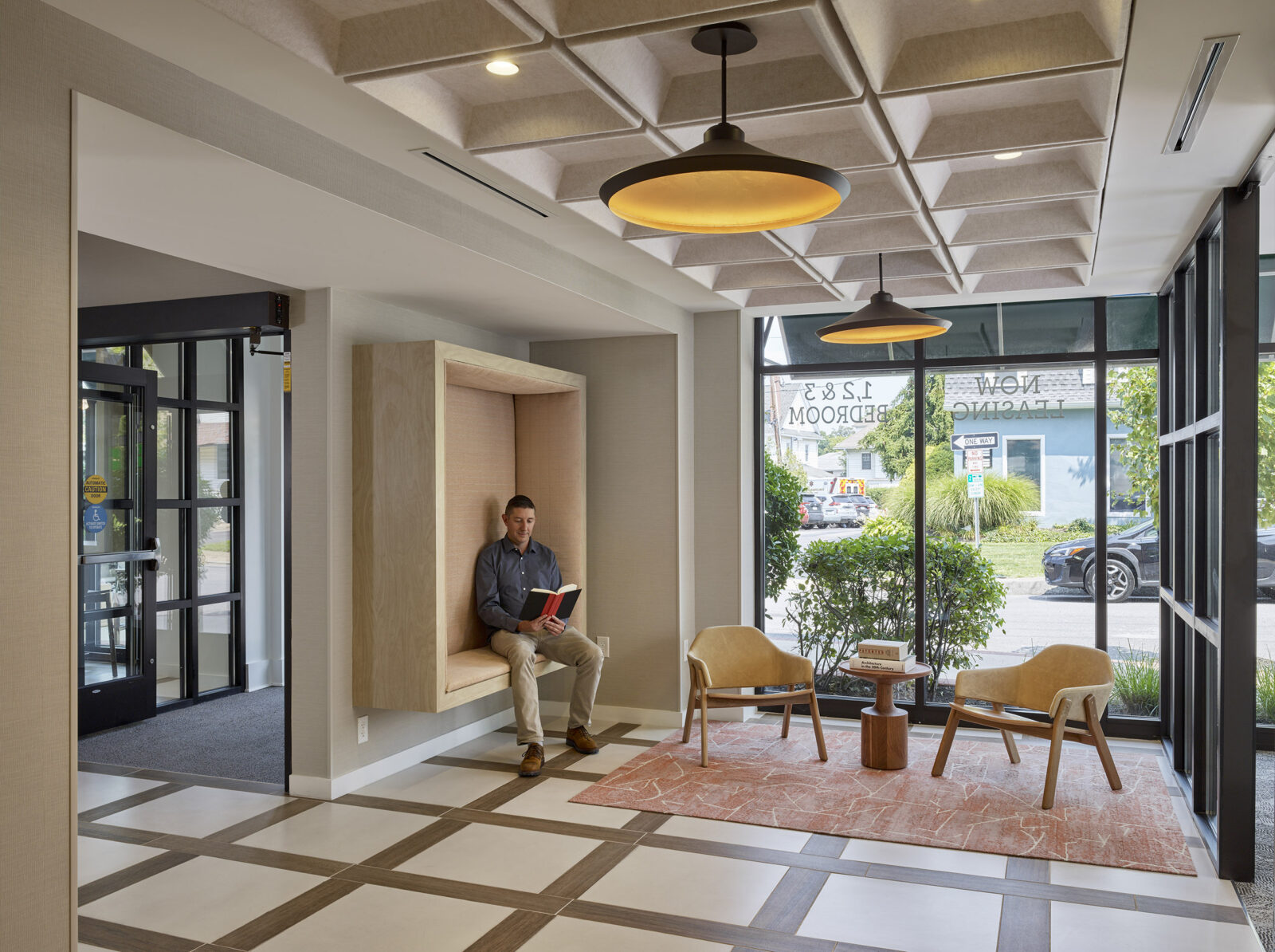 photo of the lobby of the Square, showing a man reading a book while sitting in a square-shaped seat embedded into the wall